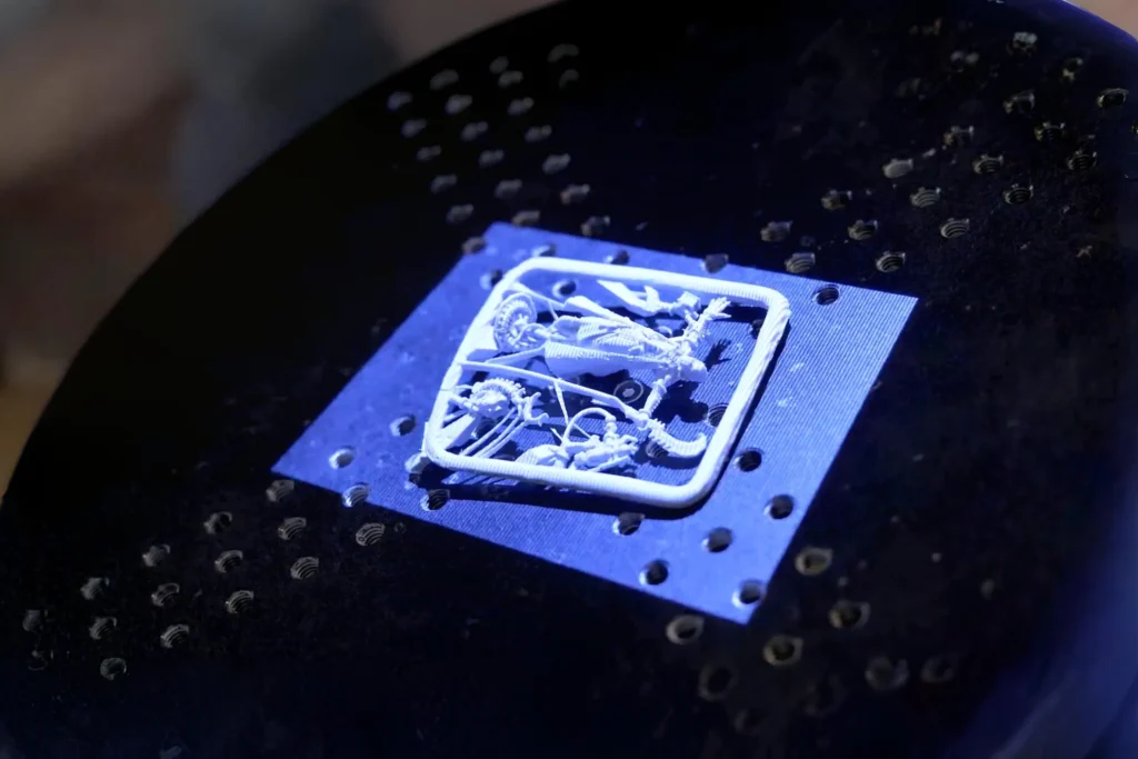 Zeiss ScanPort 3D scanner capturing detailed figurine with blue LED lighting on perforated platform for high-precision digital conversion