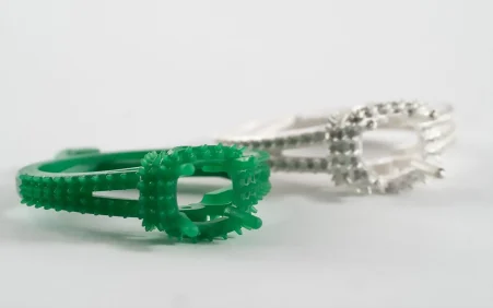 Jcast Green 20 Green 3D printed wax ring model next to finished white gold cast ring with diamond-like stones on white background