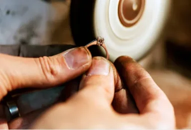 Artisan Polishing a Ring Jeweler's hands polishing gold diamond ring with rotary tool for mirror finish in workshop